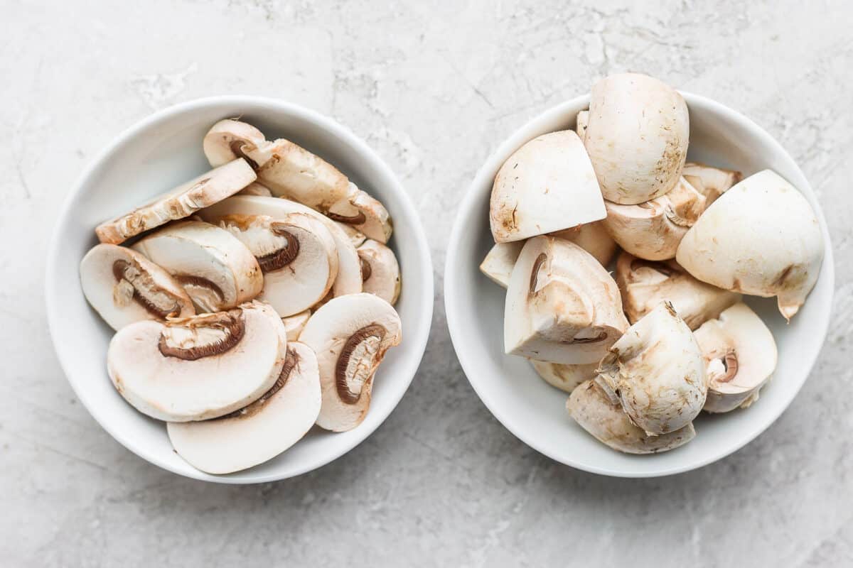 2 small bowls with different cuts of mushrooms: sliced and quartered.