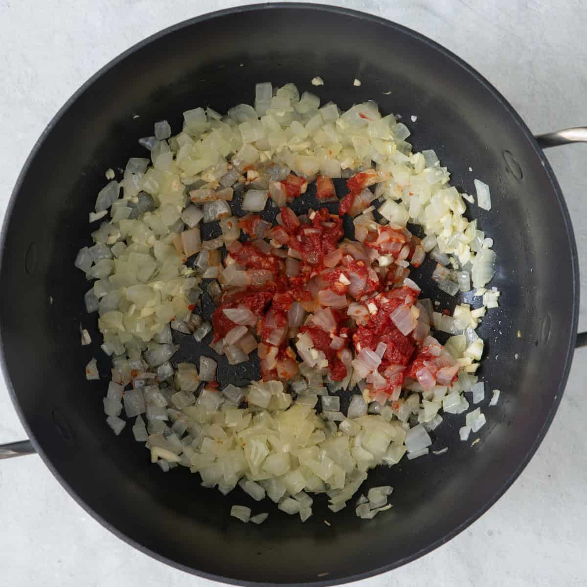 Softened onions and tomato paste in pot.