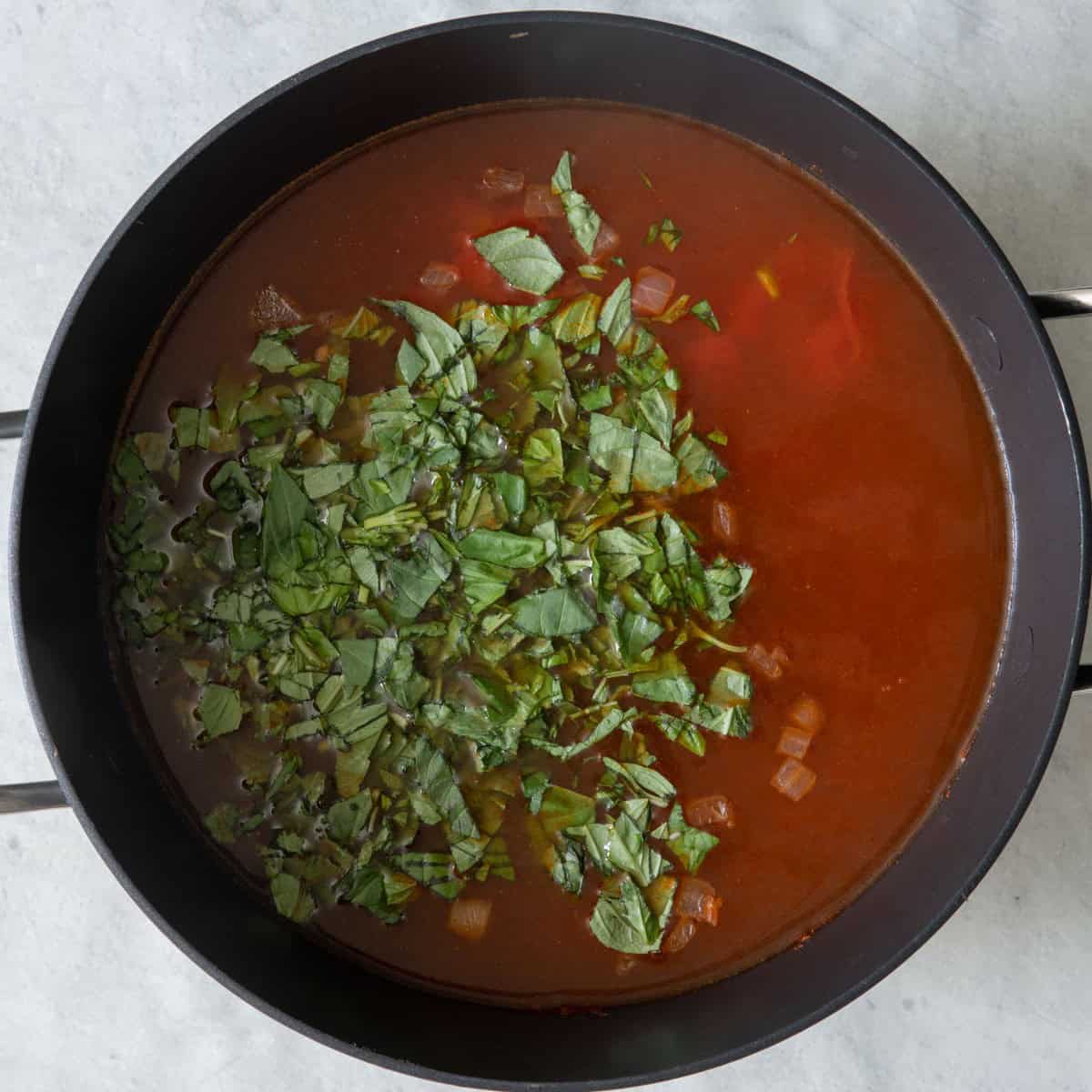 Stock, tomatoes and basil added .