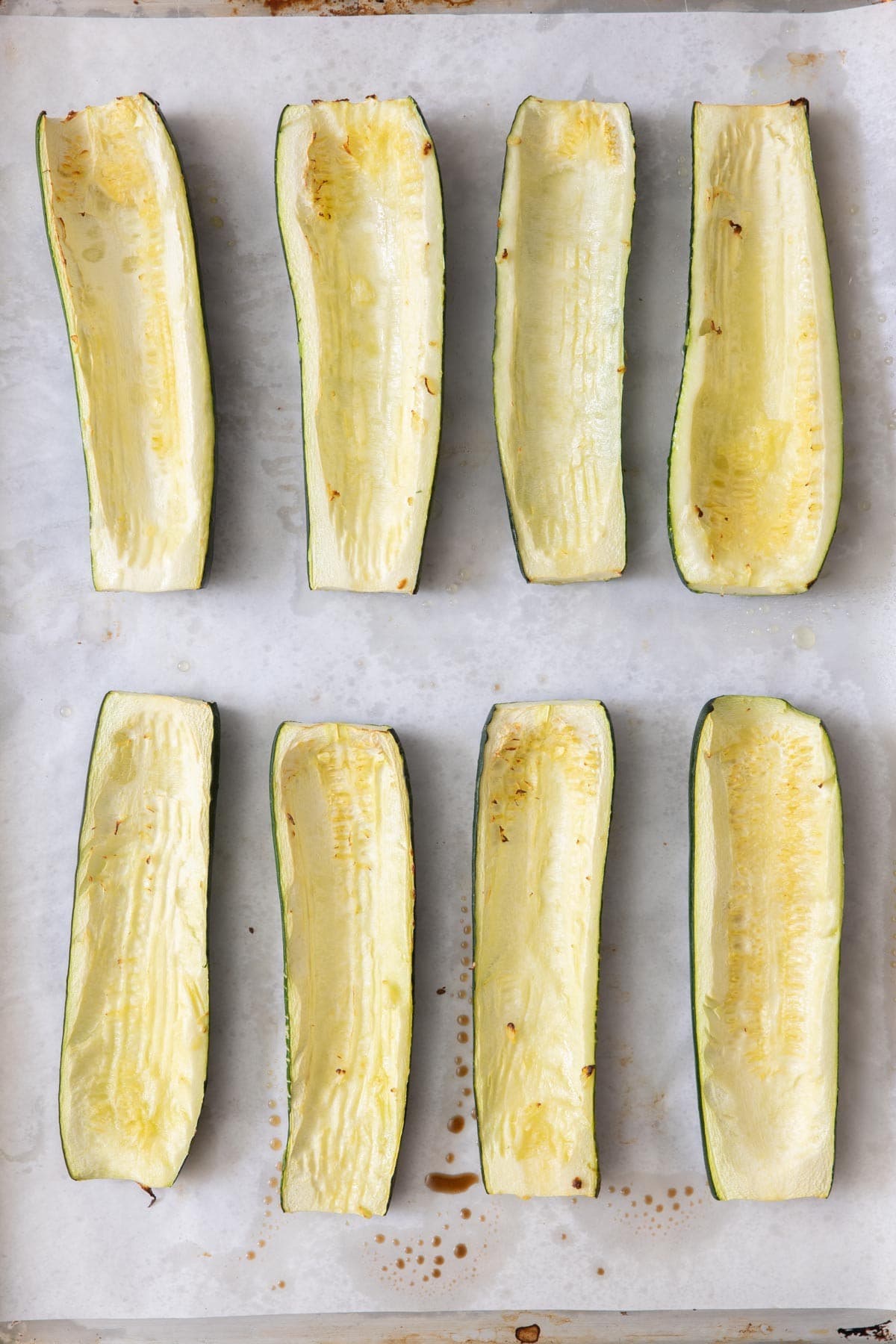 Baking dish with parchment paper and 8 zucchini halves,