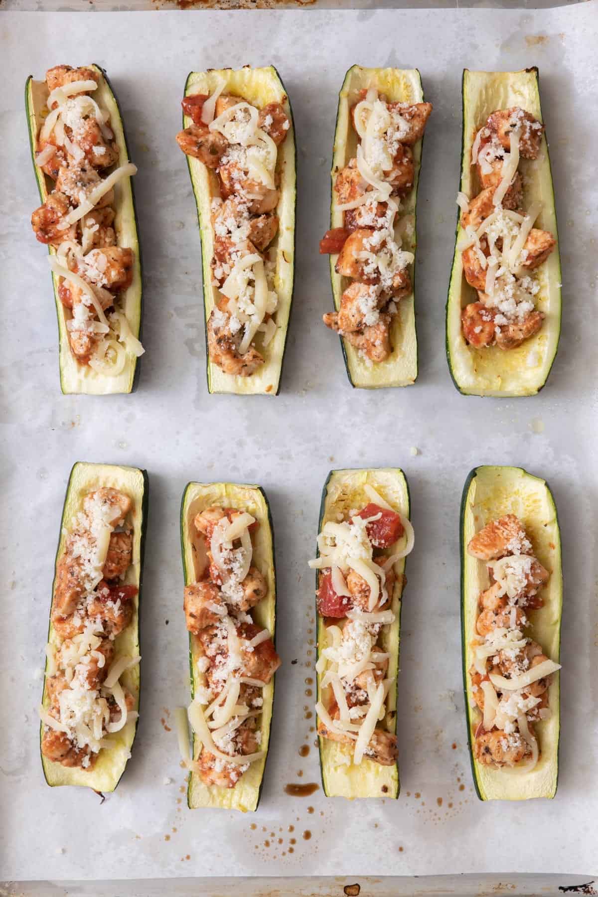 Cheeses added on top of zucchini boats.