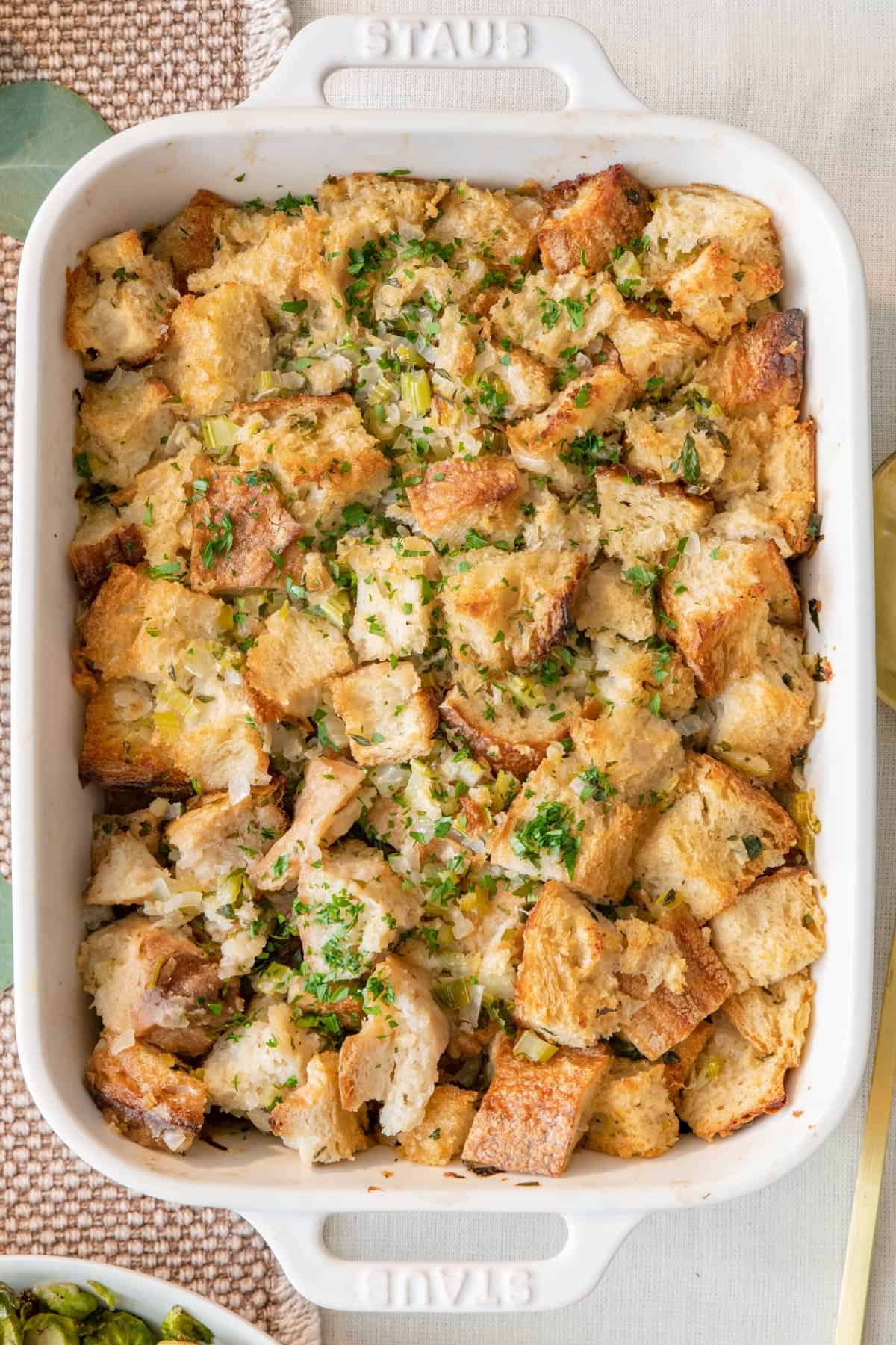 Thanksgiving stuffing in a baking dish garnished with fresh herbs.