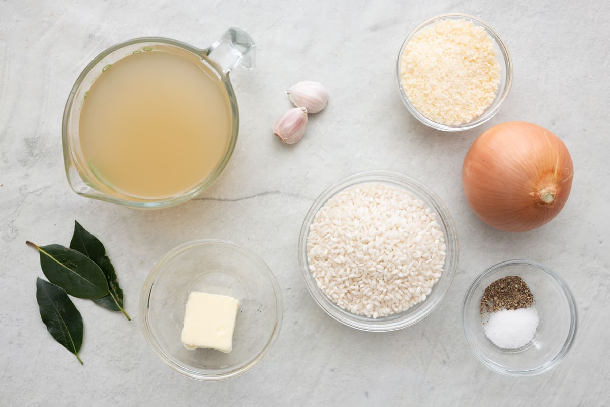 Ingredients for recipe: chicken broth, bay leaves, garlic cloves, butter, arborio rice, grated parmesan cheese, whole onion, and salt and pepper.