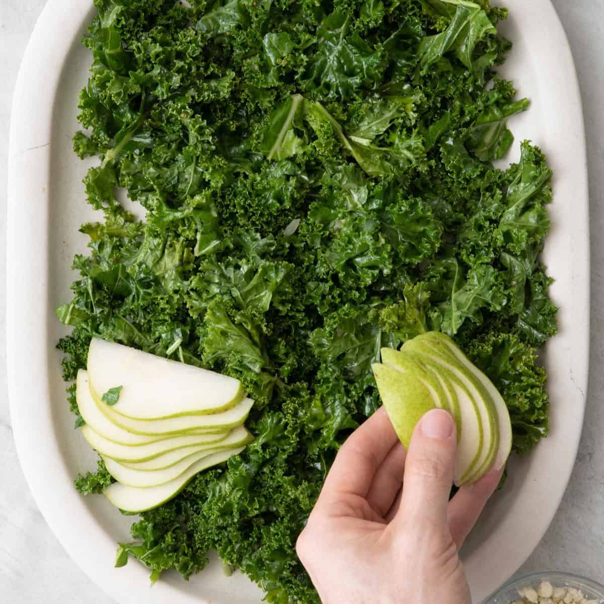 Adding a few pears slices fanned out on top of salad with other ingredients nearby.