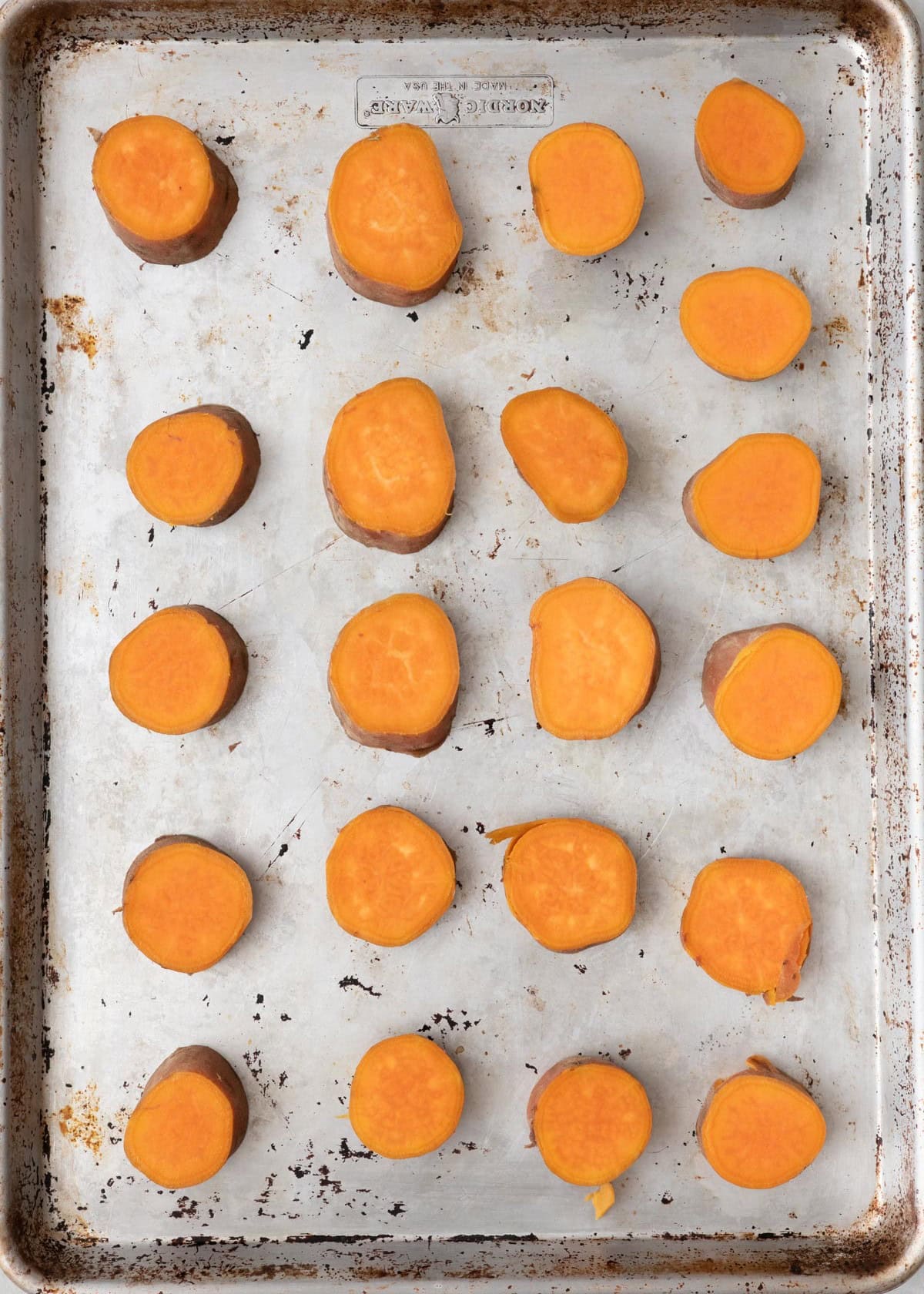 Boiled sweet potato rounds on oiled baking sheet.