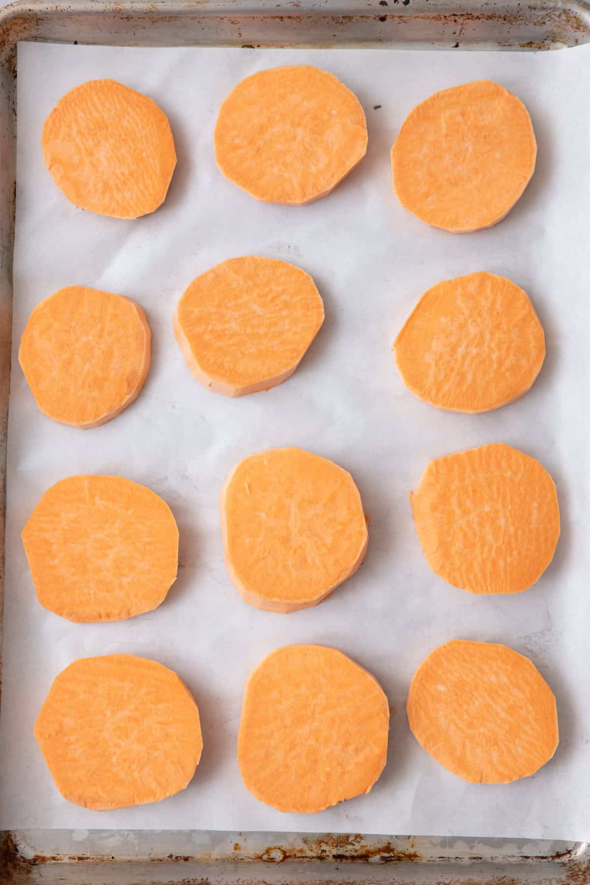 Sliced sweet potatoes on baking sheet.