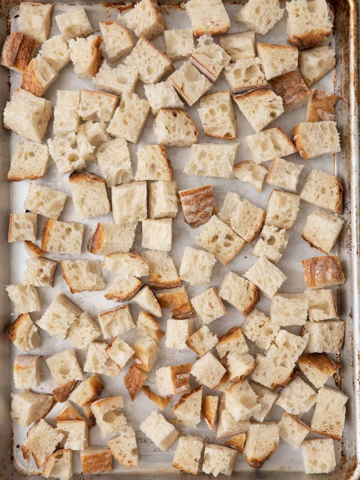 Bread cubes on rimmed baking sheet before baking.