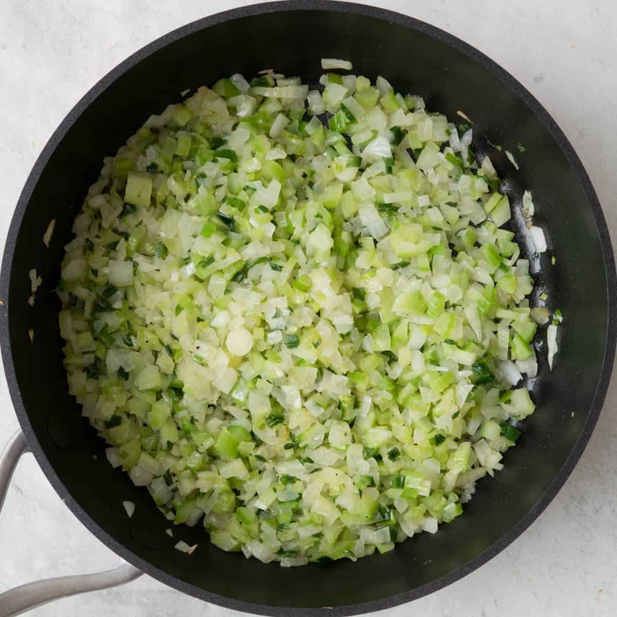 Large skillet with melted butter, oil and cooked onion, celery, green onions, thyme, salt and pepper.