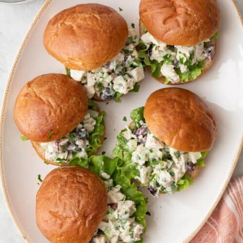 Turkey salad sandwiches stacked on a small serving plate/bowl with sandwiches hanging over the edges.