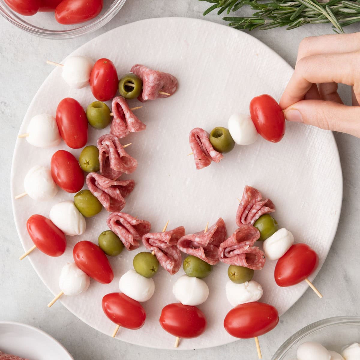 Skewering some ingredients with some on a round board already.