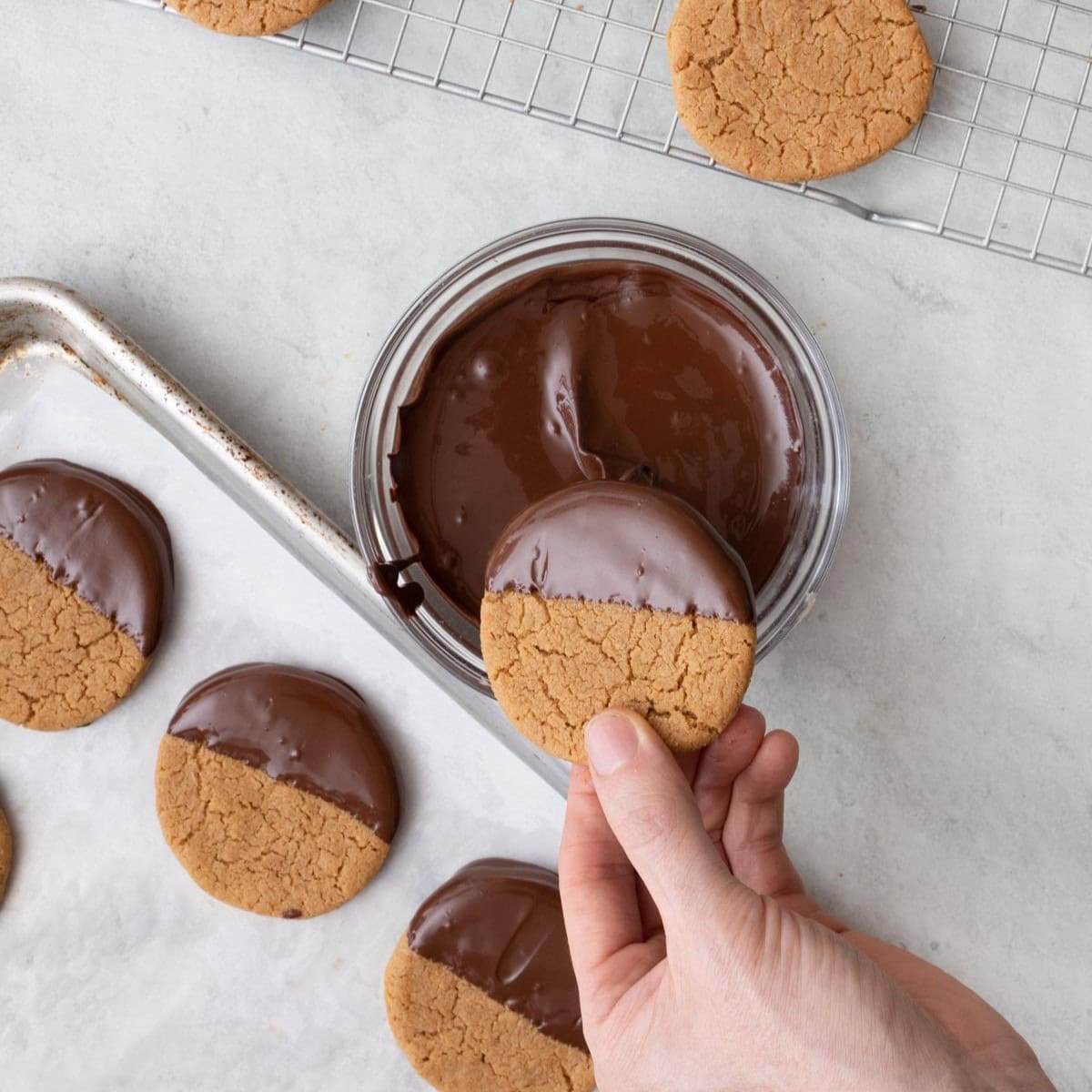 Dipping cookie into melted chocolate.