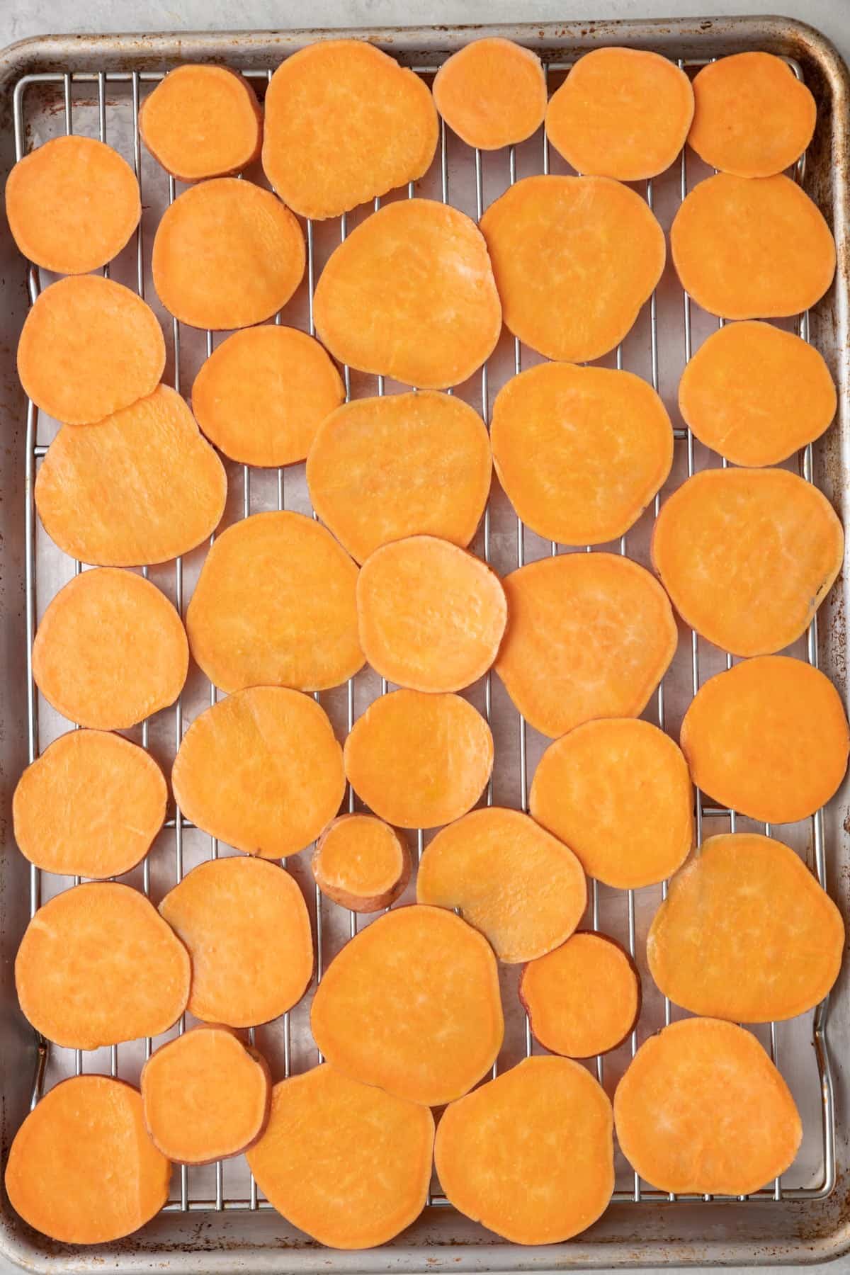 Slices on wire rack on top of a baking sheet before baking.