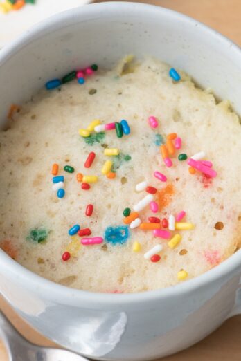 Vanilla mug cake with a spoon nearby.