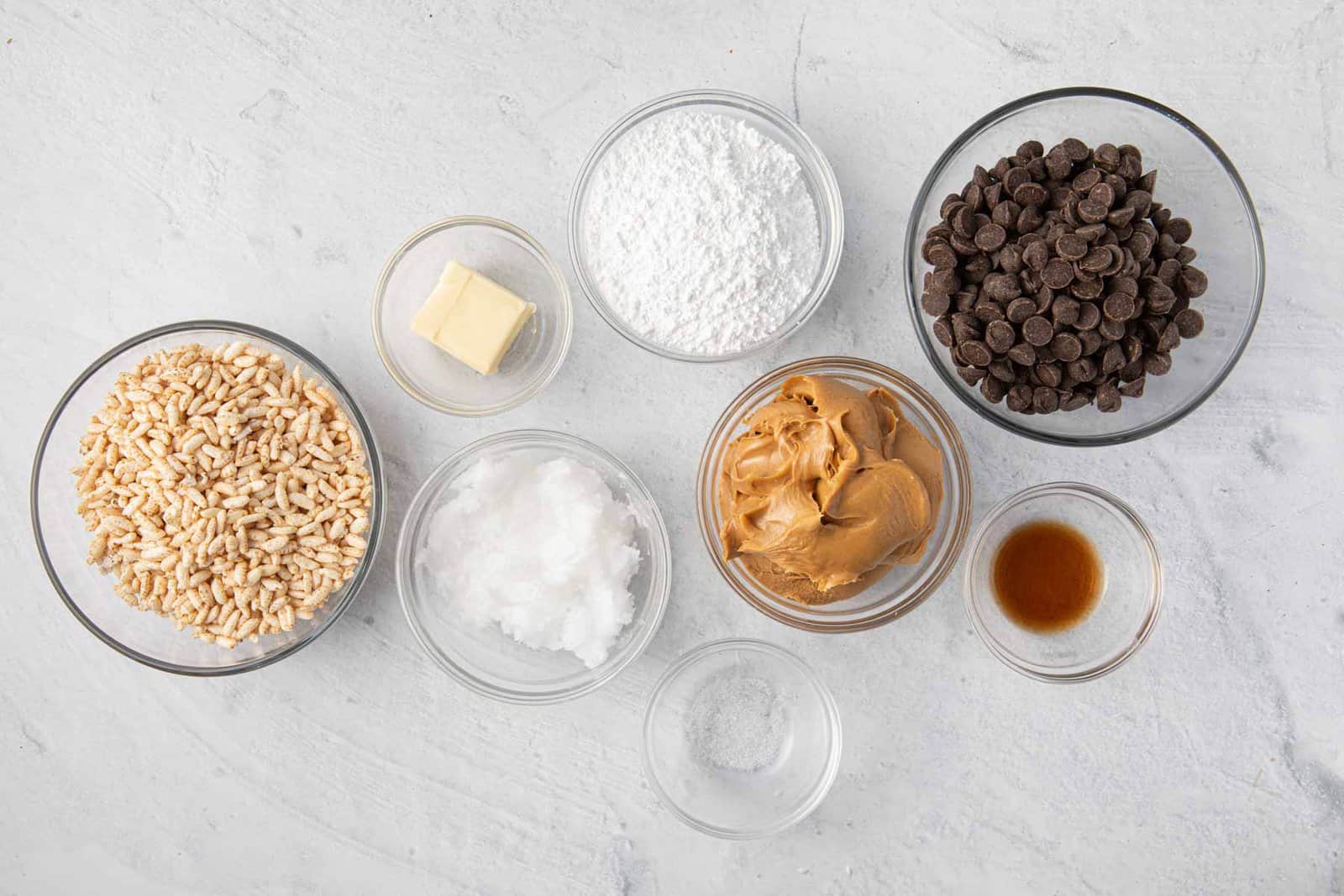 Ingredients for recipe: puffed rice cereal, butter, powdered sugar, coconut oil, salt, peanut butter, chocolate chips, and vanilla.