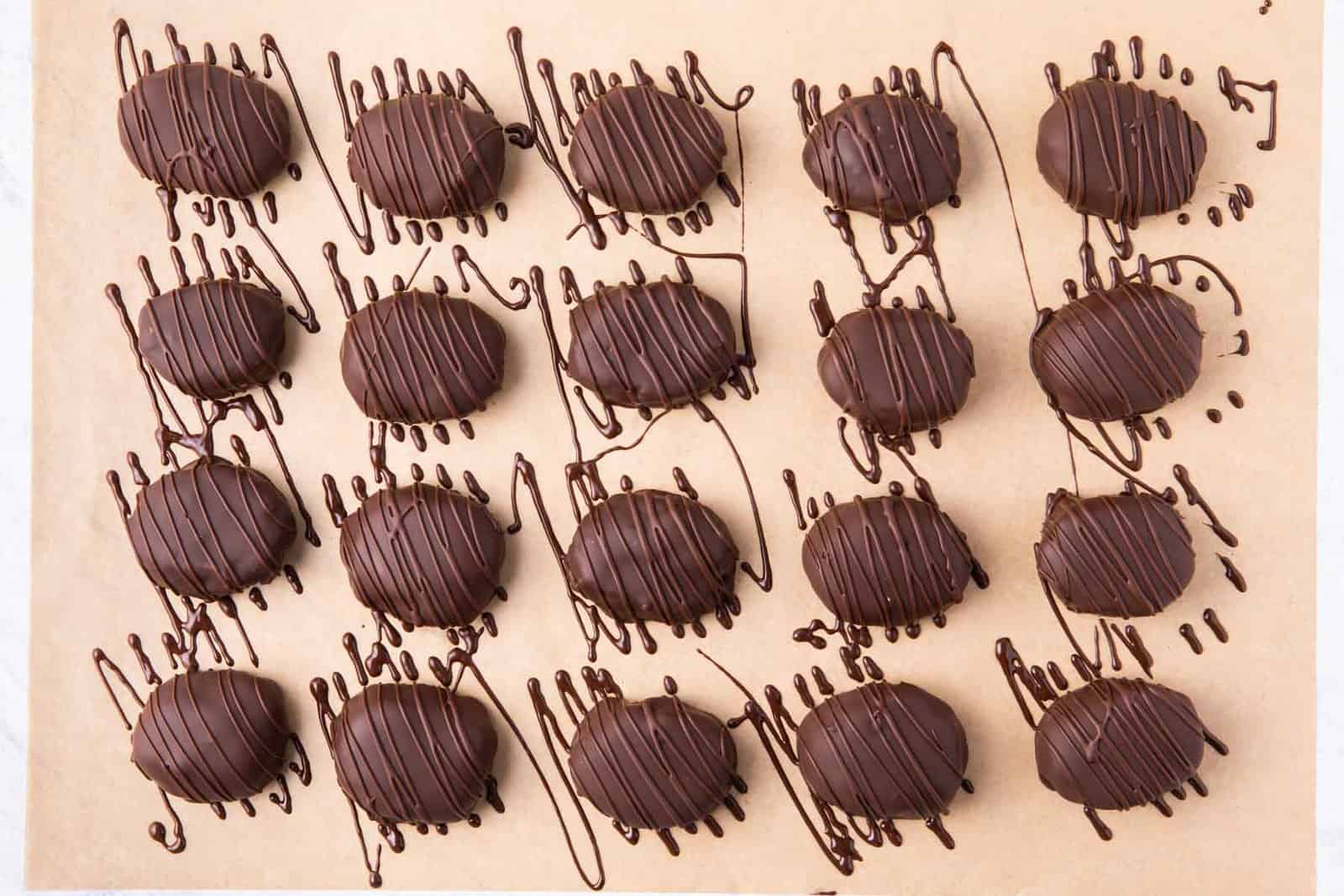 Chocolate peanut butter eggs on parchment paper with chocolate drizzle added.