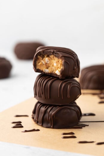 3 peanut butter eggs with chocolate coating stacked on top of each other with a bite taken out of the top egg.