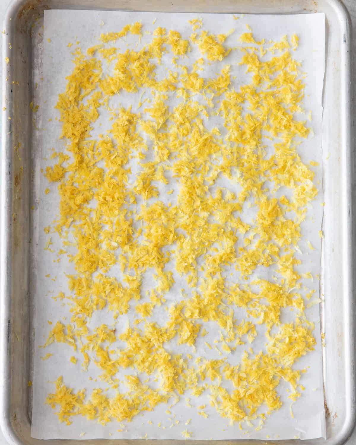 Lemon zest spread evenly on a small parchment lined baking sheet before drying.
