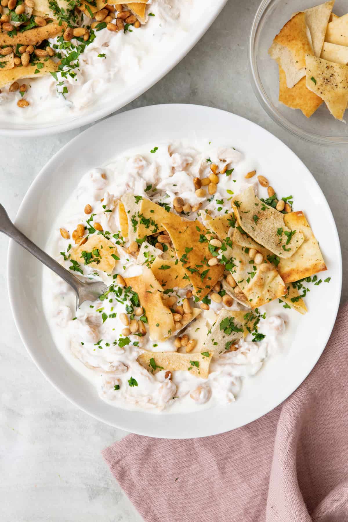 Chicken Fatteh in a a wide shallow bowl with a spoon dipped in.