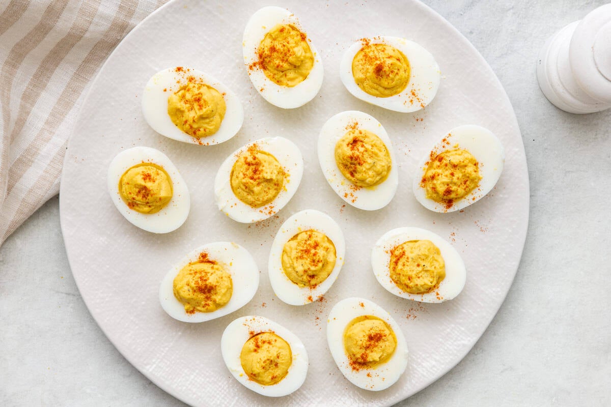 Plate with 12 deviled eggs sprinkled with paprika.