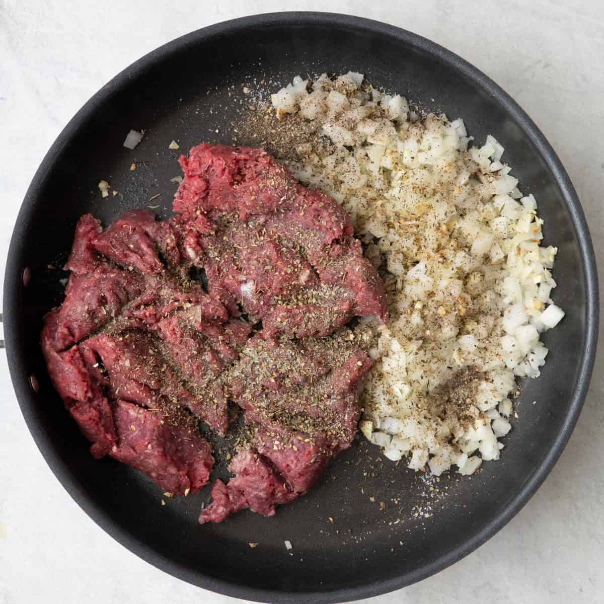 Ground beef, onions and garlic in a large skillet, with Italian seasoning, salt and pepper added before cooking.