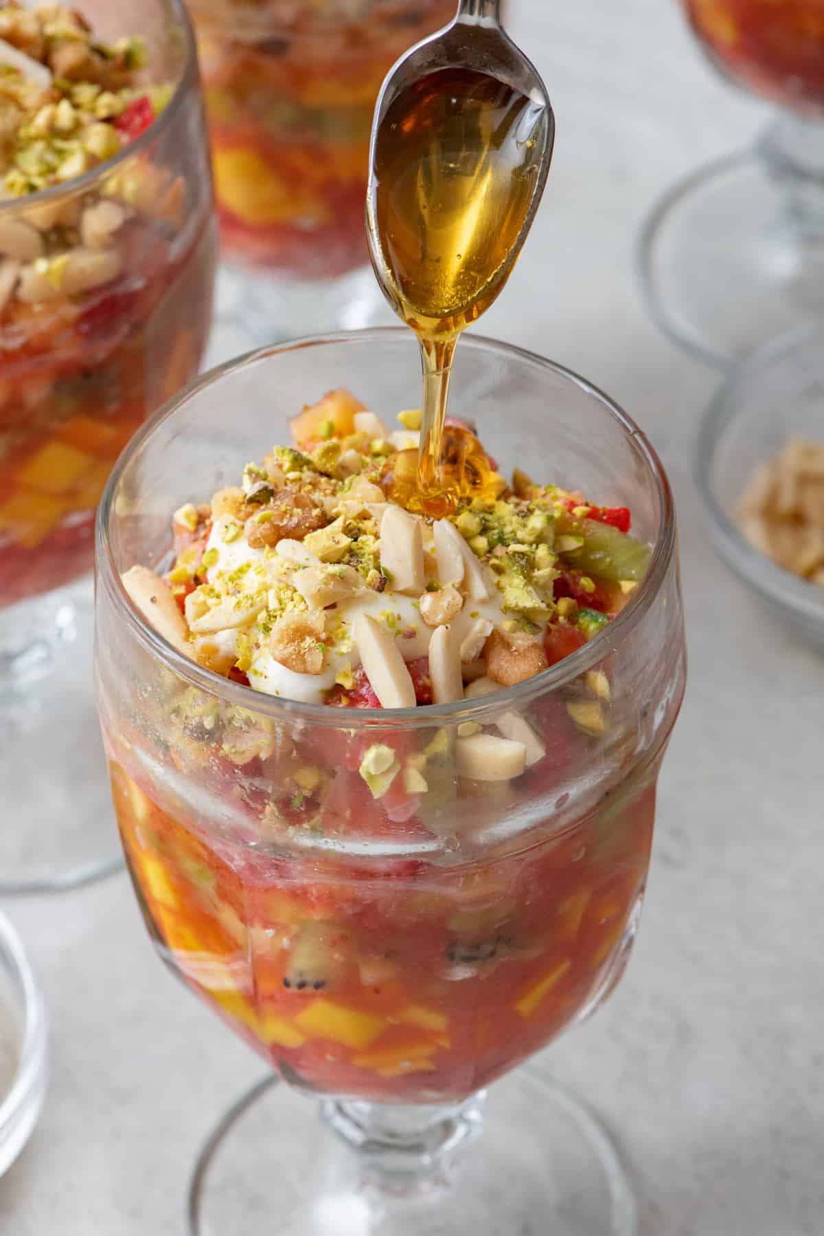 Honey being drizzled on top of fruit cocktail.