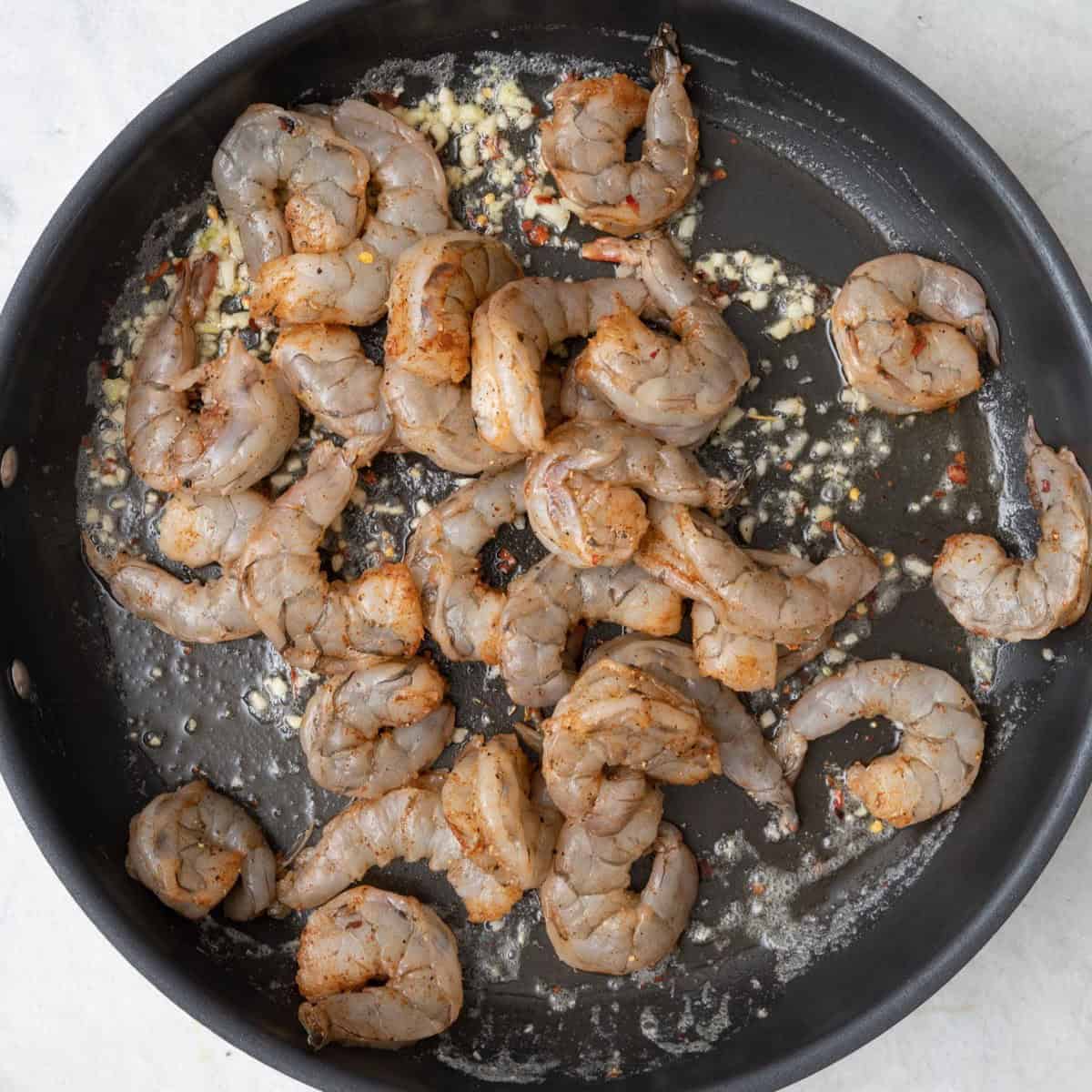 Large skillet with shrimp added before cooked.