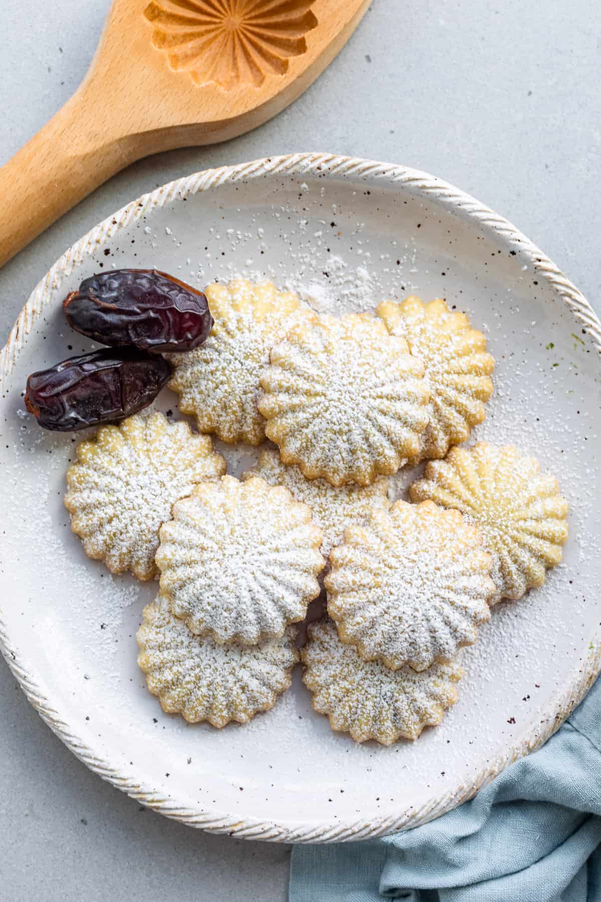 Date filled maamoul cookies o a plate with a few whole dates.