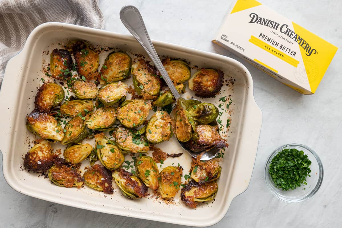 Parmesan crusted brussel sprouts made with Danish Creamy Premium Sea Salted Butter sticks in a baking dish to show crusted cut side.