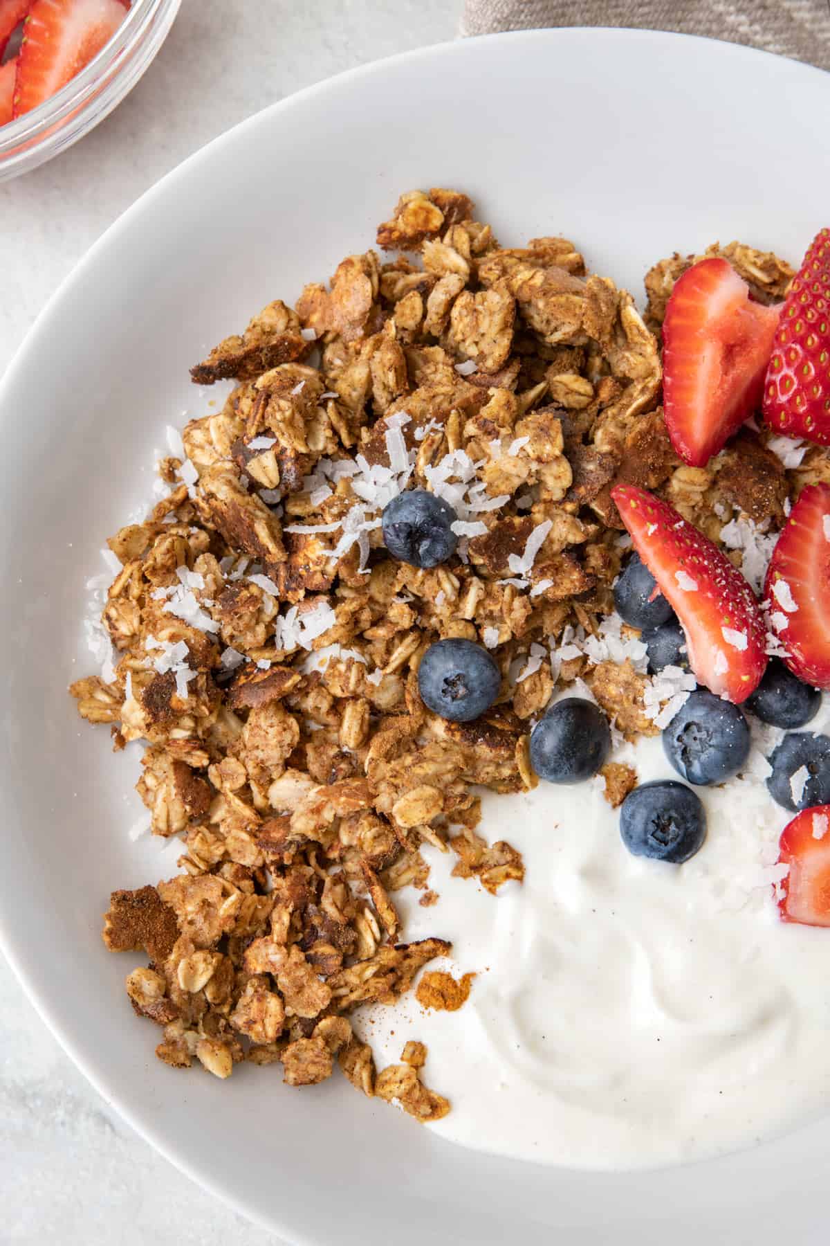 Close shot of scrambled oats in a bowl with strawberries, blueberries, and yogurt.