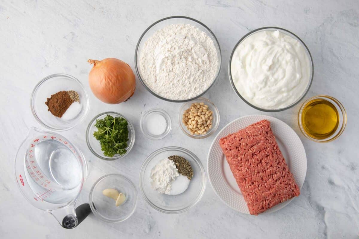 Ingredients for recipe: water, spices, onion, herbs, garlic, flour, salt, cornstarch, pinenuts, yogurt, ground beef, and oil.
