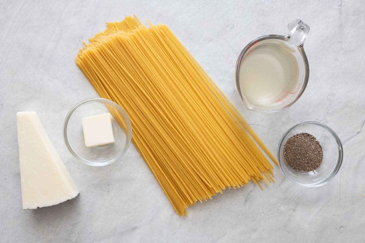 Ingredients for recipe: block of parmesan cheese, butter, dry pasta, pasta water, and pepper.