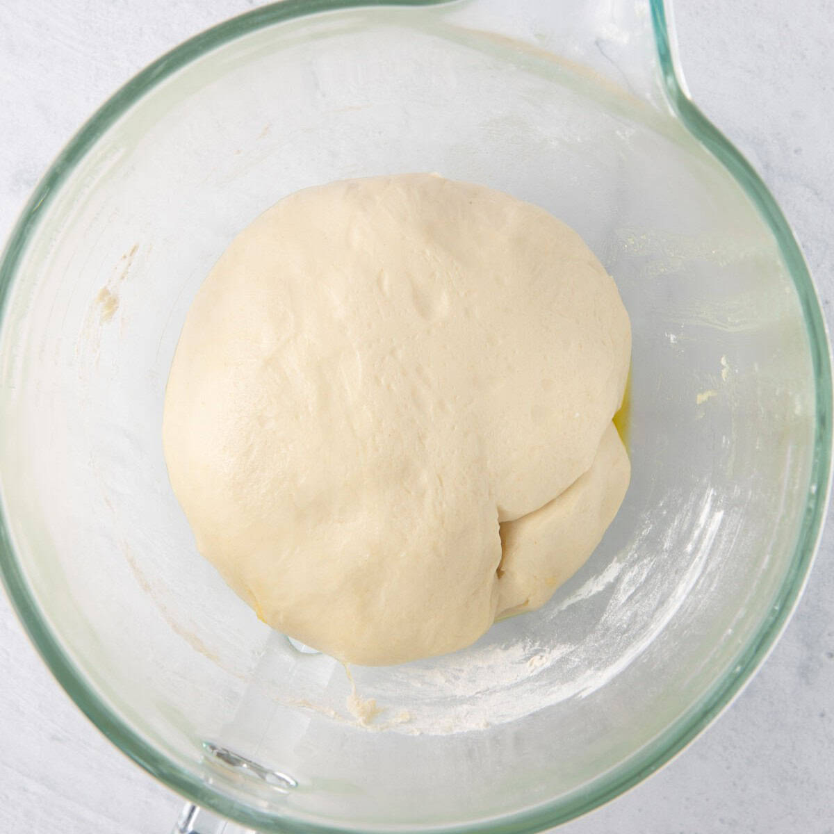 Dough after doubling its volume in the bowl with plastic wrap removed.