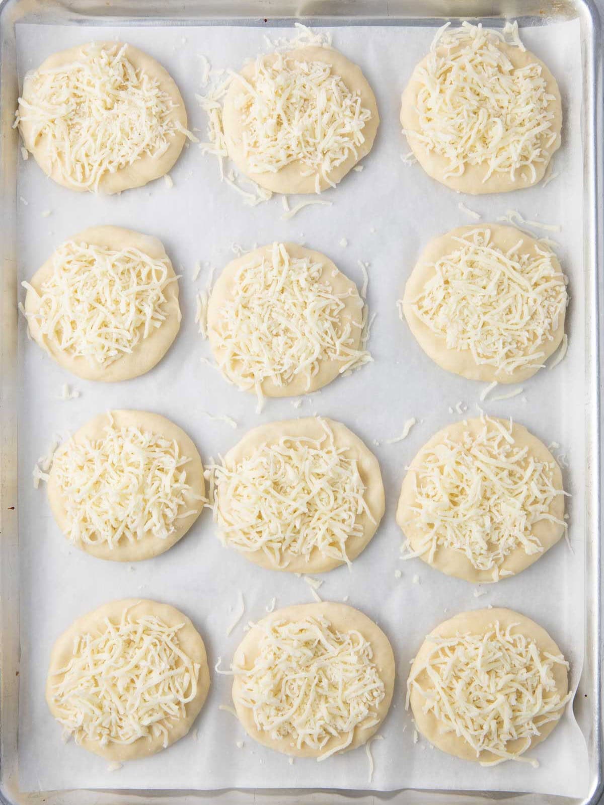 Flatbreads with cheese before baking.
