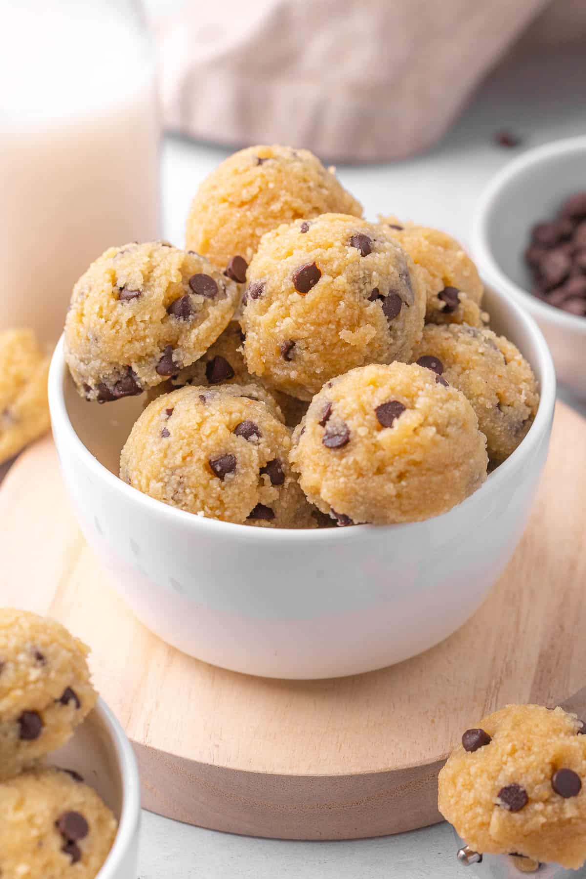 Chocolate chip edible cookie dough in a small bowl with more around.