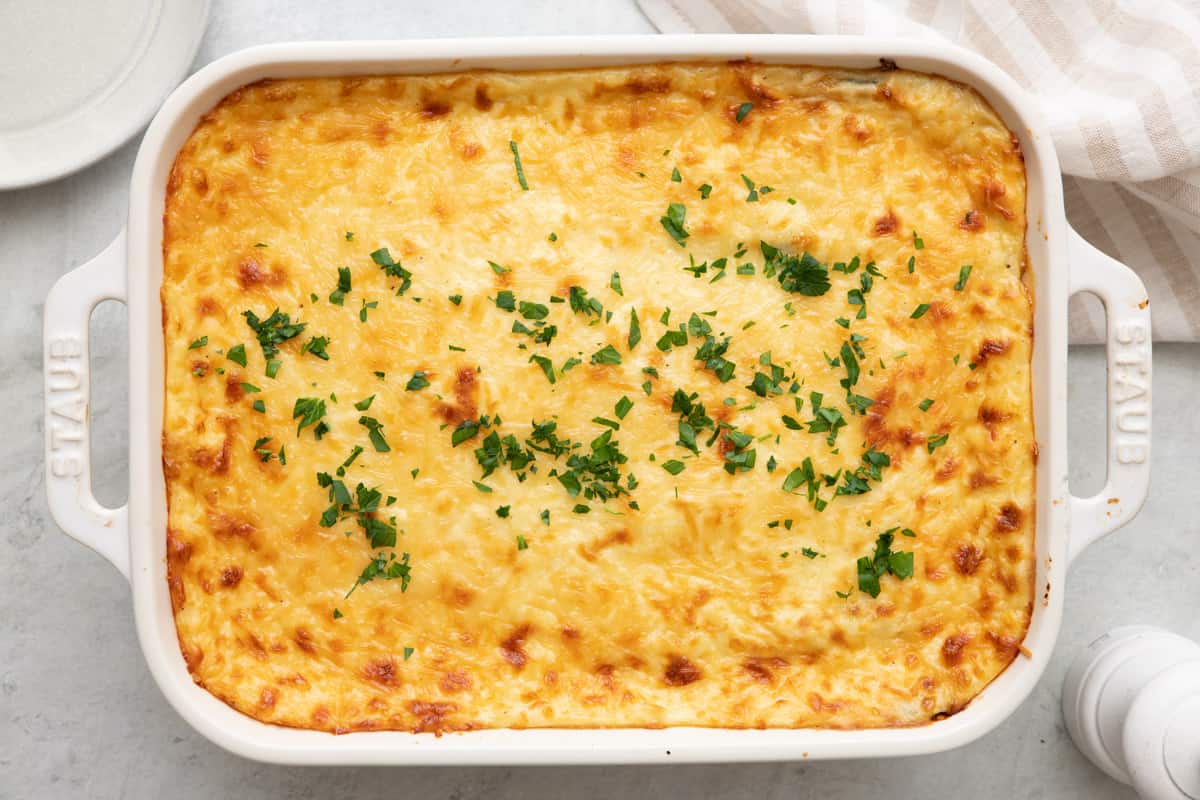 Eggplant moussaka in a baking dish garnished with fresh parsley.