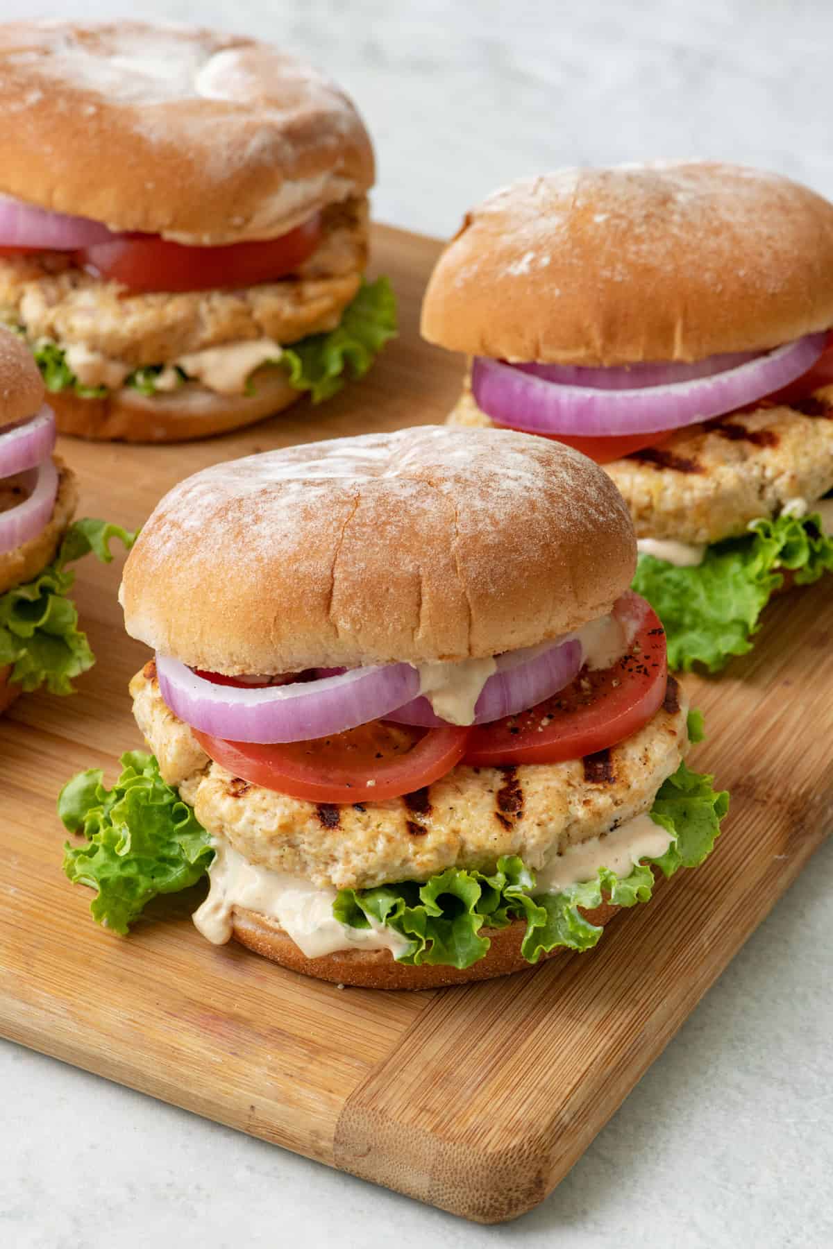 Grilled yogurt chicken burgers on a cutting board.