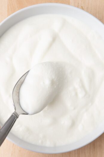 Yogurt in small bowl with spoon lifting up some yogurt.