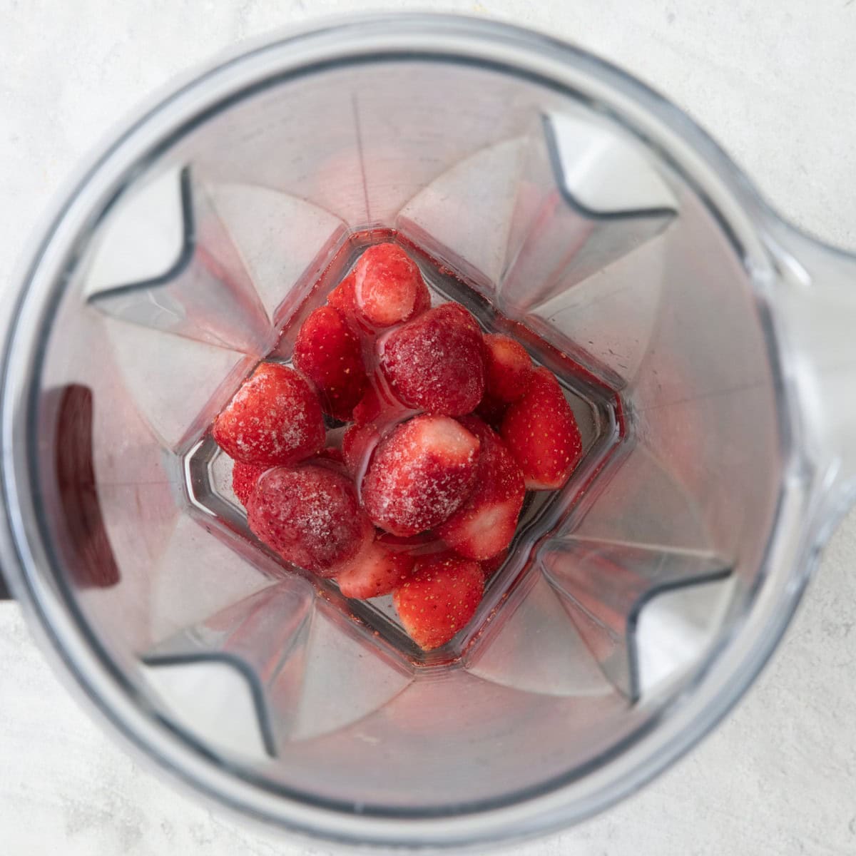 Strawberries, water, and rose water in a small blender before blending.