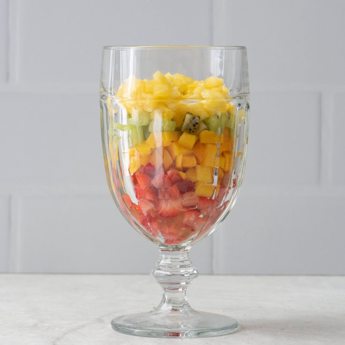 Chopped fruit layered into 4 serving glasses.