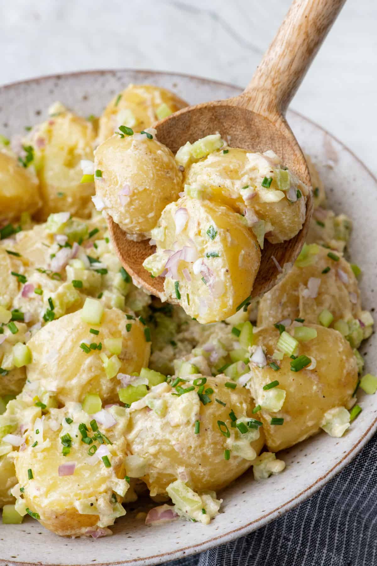 Mustard potato salad with a serving spoon scooping some up.