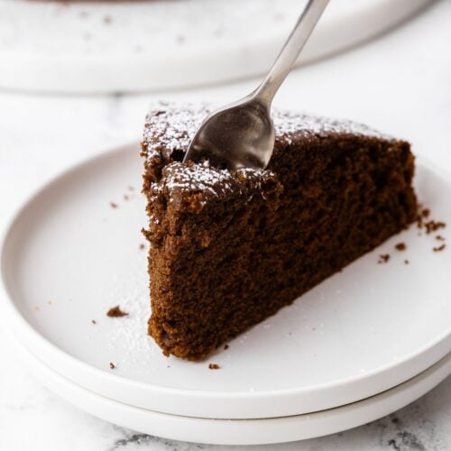 Overhead shot of chocolate olive oil cake cut into 8 slices and sprinkled with powdered sugar.