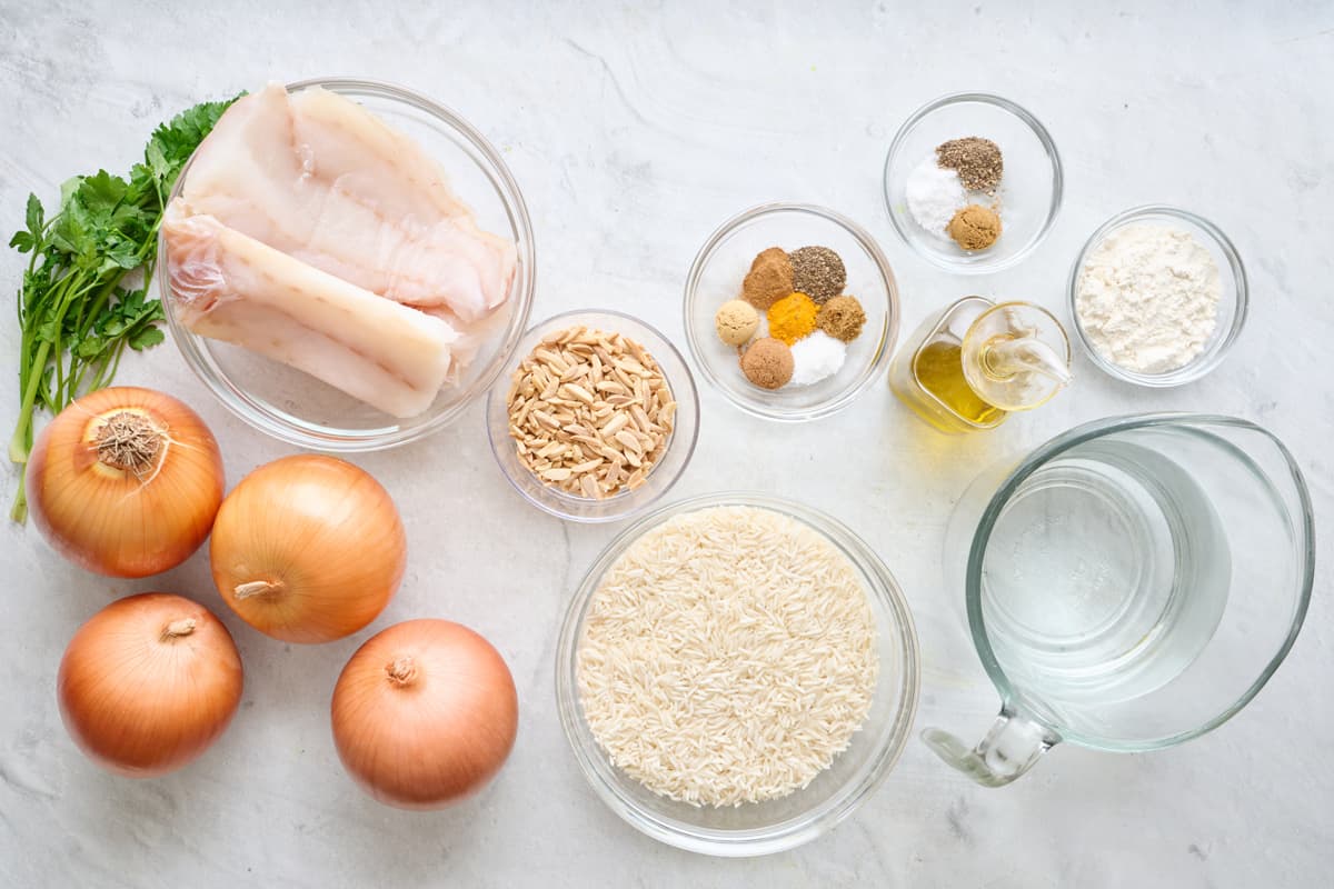 Ingredients for recipe before prepping: fish, parsley, onions, almonds, spices, rice, oil, flour and water.
