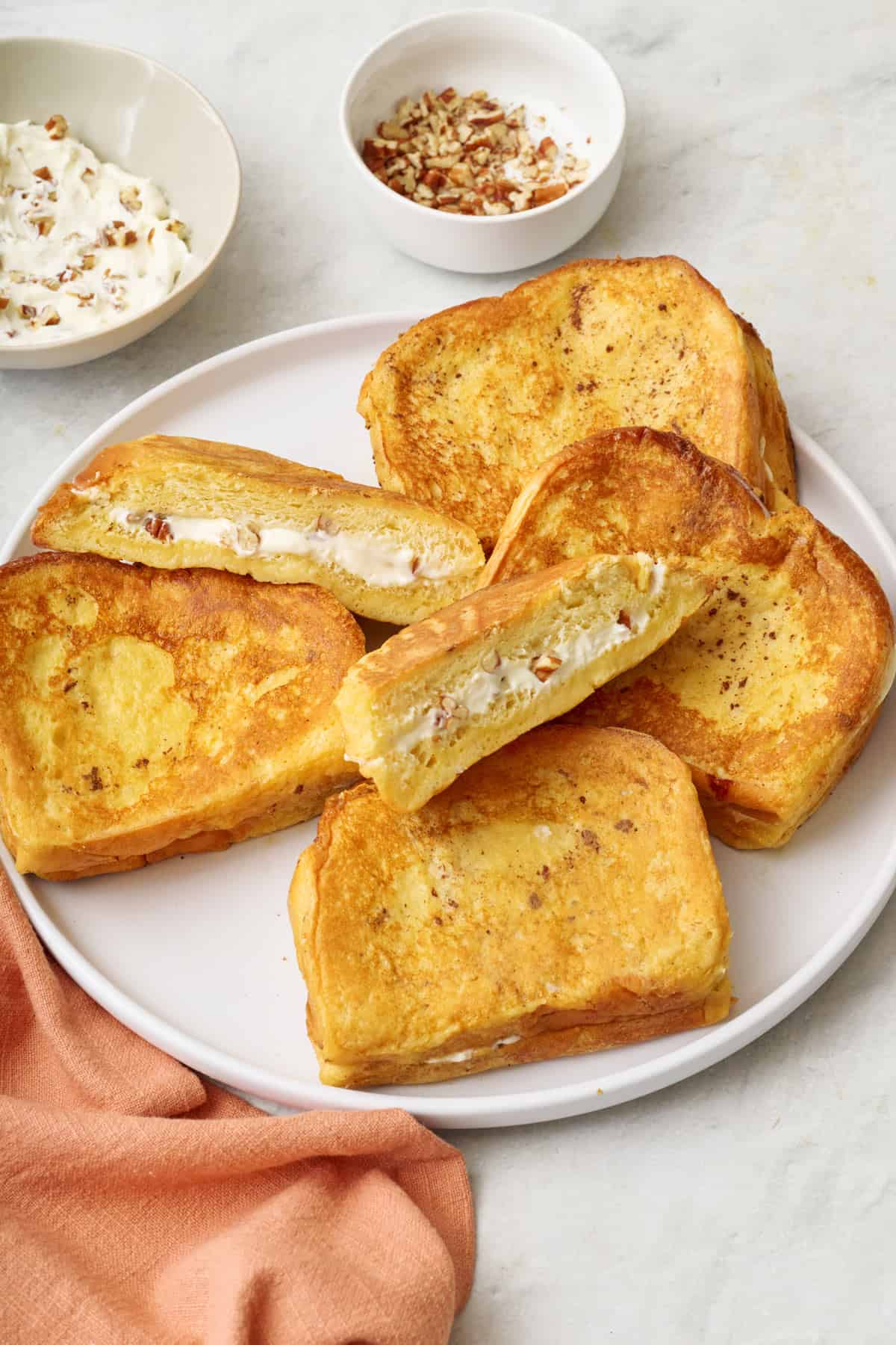 Top view of two servings of stuffed french toast sitting on a plate with maple syrup and sliced bananas