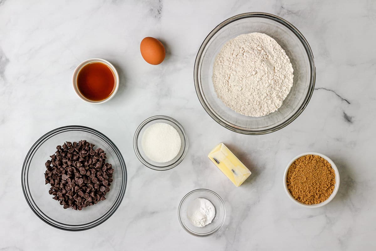 Ingredients for recipe: chocolate chips, vanilla, an egg, sugar, baking powder and salt, butter stick, flour, and brown sugar.
