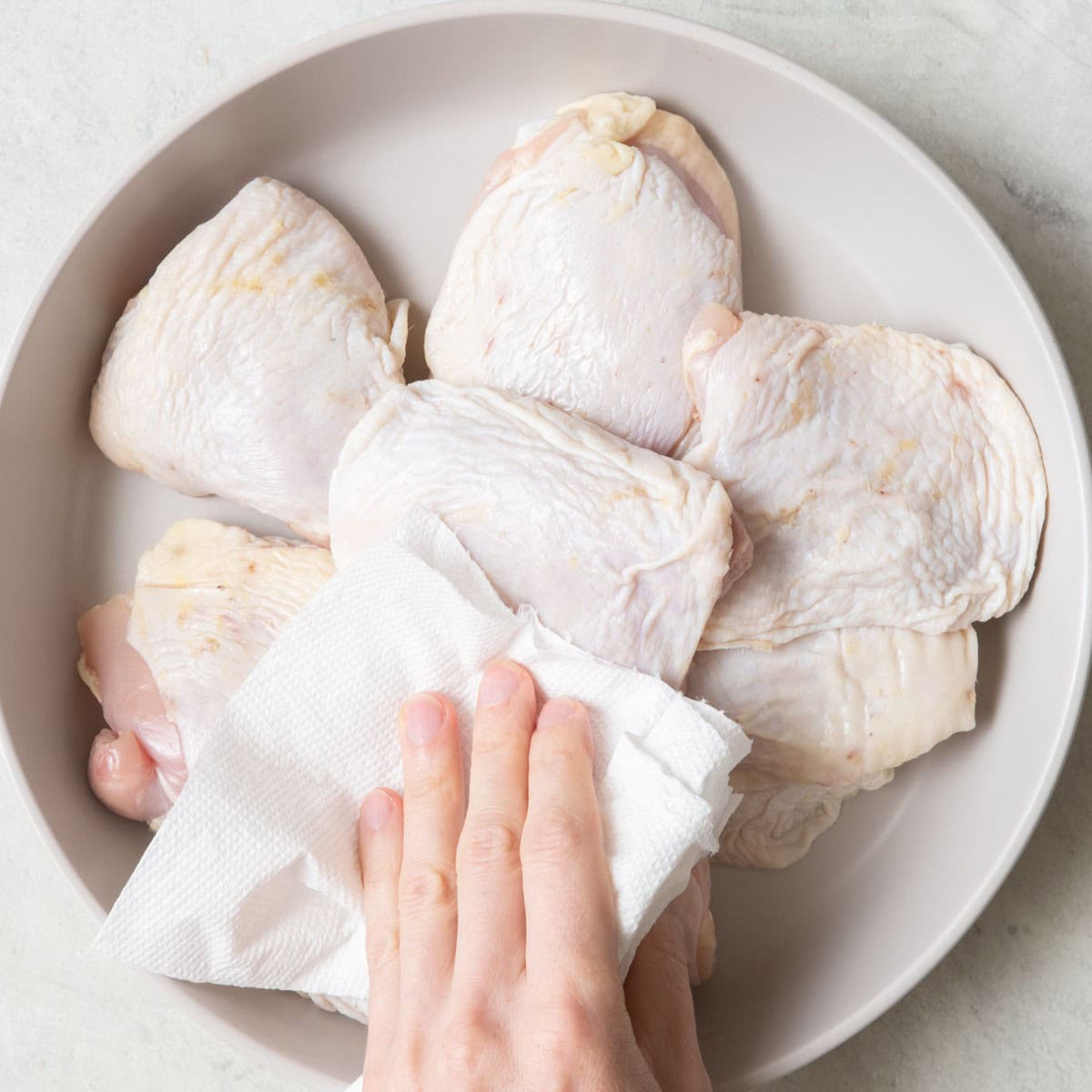 6 Chicken thighs in a large shallow bowl with paper towels patting them dry.
