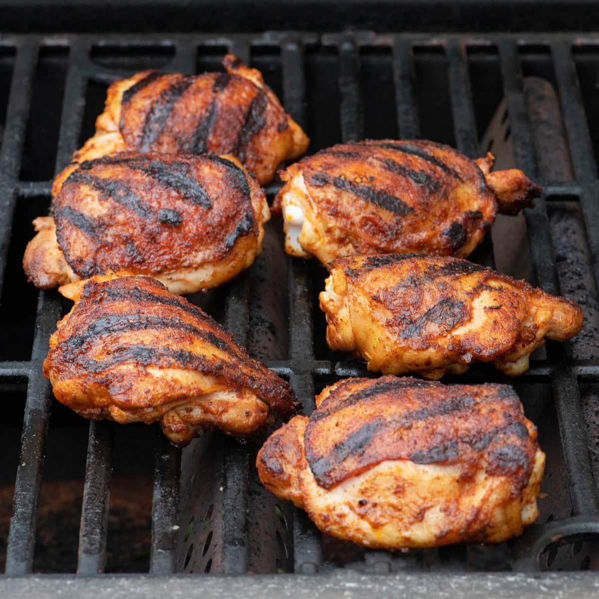 Chicken flipped on the grill to show crisped skin.