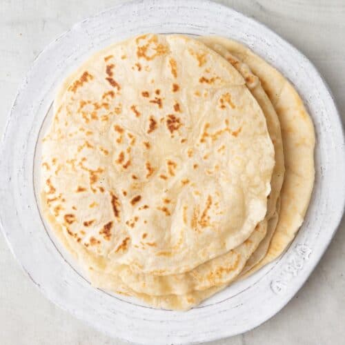 A stack of flour tortillas on a plate.