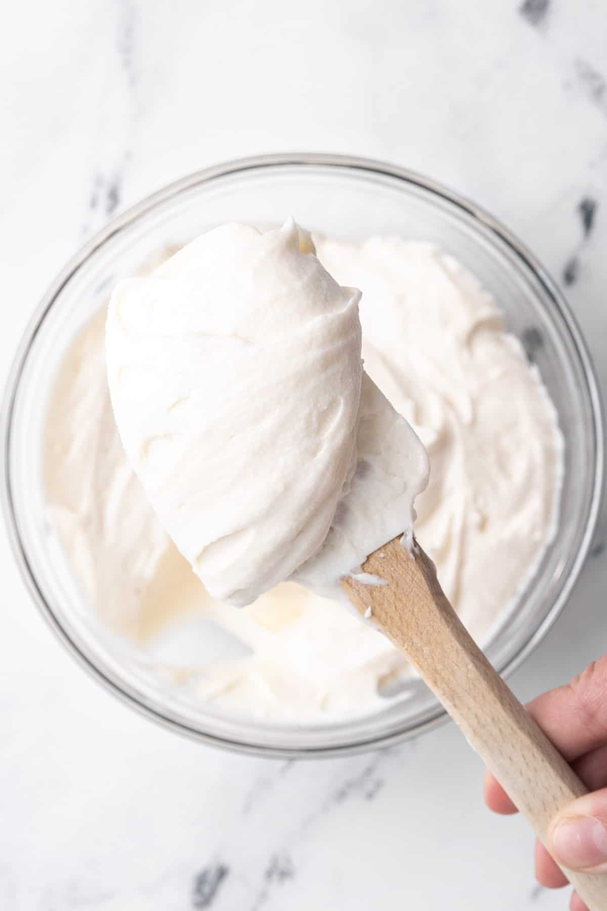 Spatula lifting up a scoop of buttercream to show thick, creamy consistency.