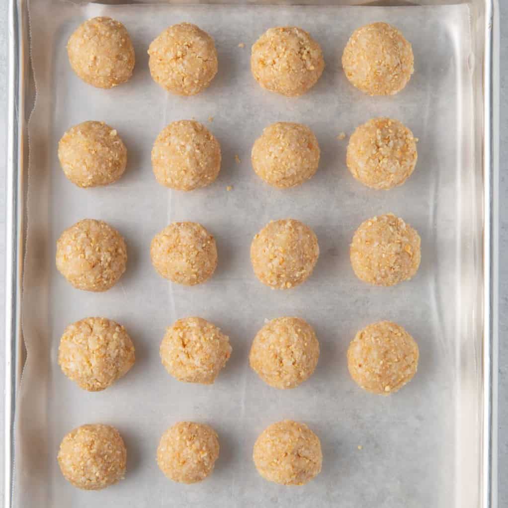 Parchment lined baking sheet with all the coconut balls.