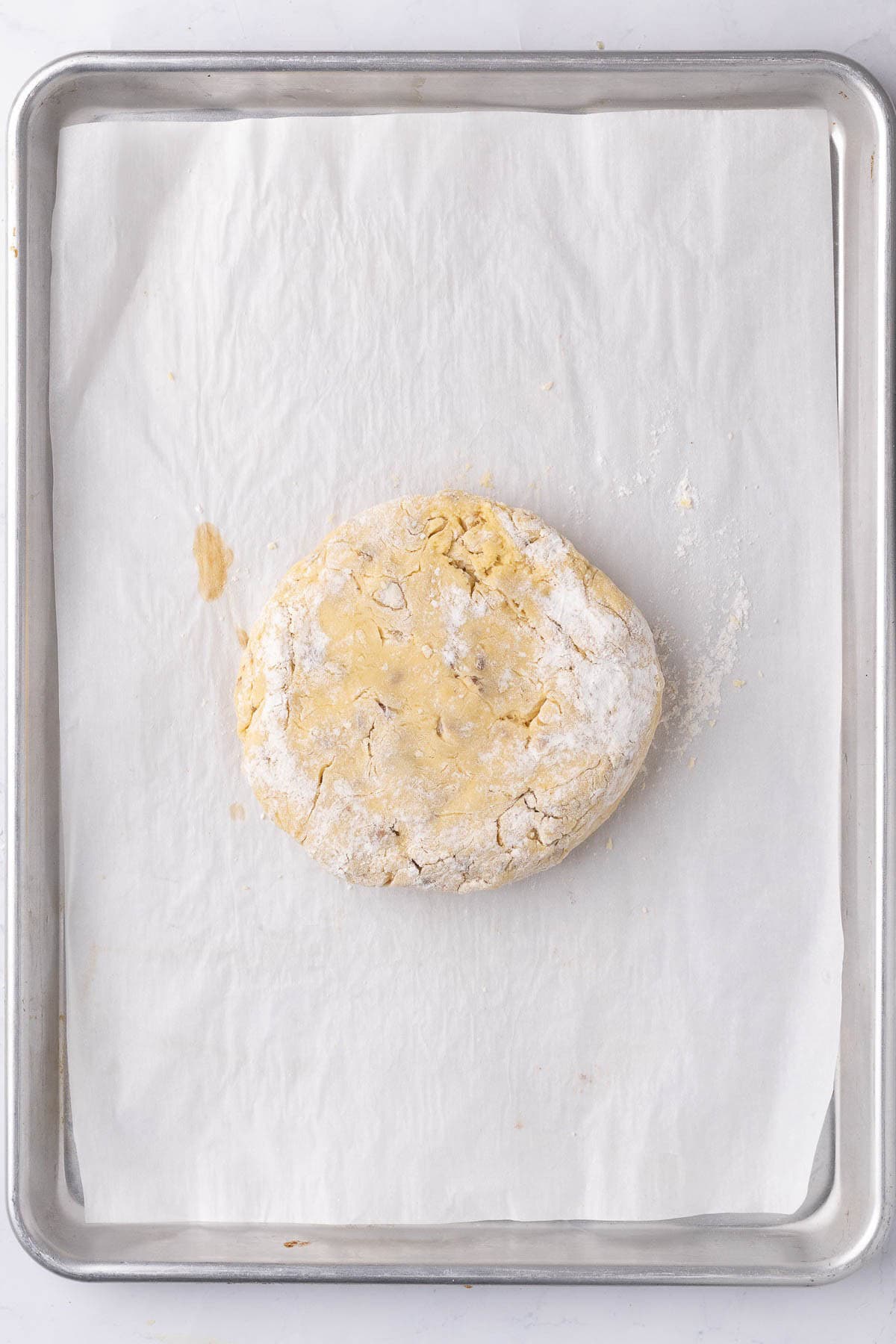 Kneaded dough transferred to parchment paper lined baking sheet before shaped